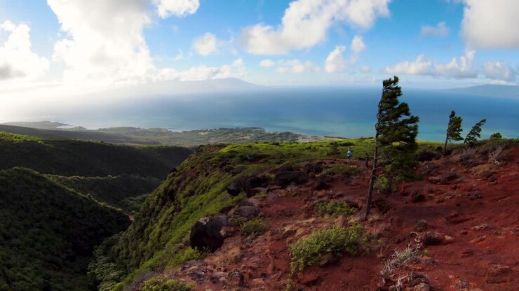 Vista aerea FPV che mostra due operatori che controllano il drone in cima alle montagne di Molokai, vista posteriore.