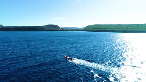 small fishing dinghy vessel motors through open ocean off coast of island