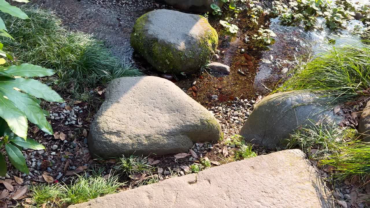 Hidas panorointikuva perinteisen japanilaisen kivipolun ja rauhallisen zen-kivipuutarhan yli.