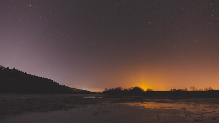Timelapse magico del movimento delle stelle nel cielo notturno sopra un fiume innevato vicino alla foresta