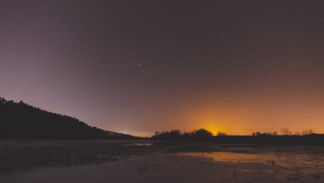 un lapso de tiempo mágico del movimiento de las estrellas en el cielo nocturno sobre un río cubierto de nieve cerca del bosque