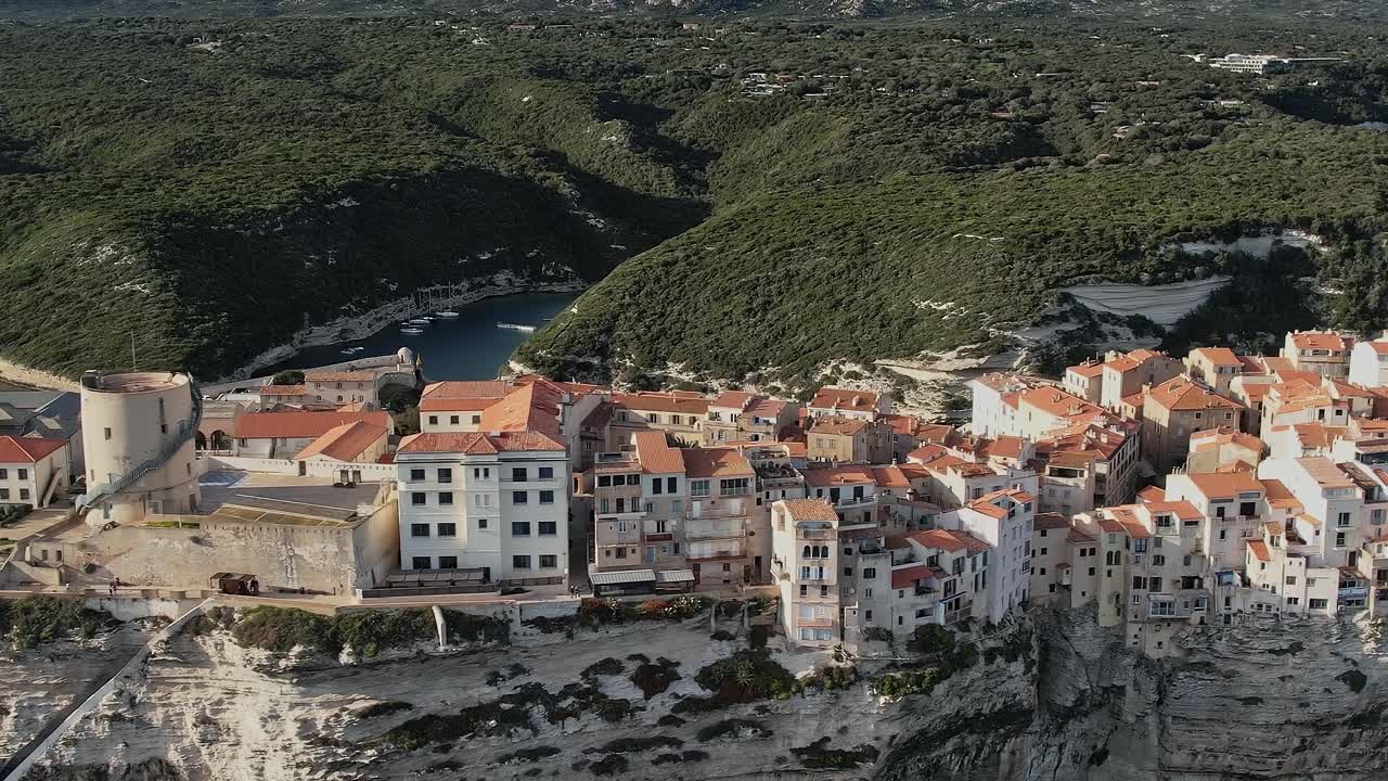 Vista della città di Bonifacio sulle scogliere in Corsica con colline verdi e porto