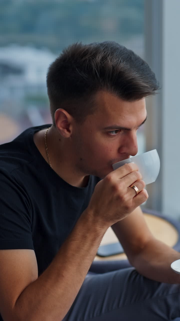 Man drinking coffee by window