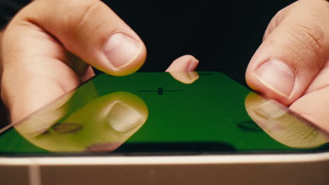 hands holding a smartphone with a green screen