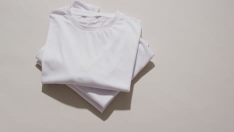 video de una pila de camisetas blancas plegadas con espacio de copia en un fondo blanco