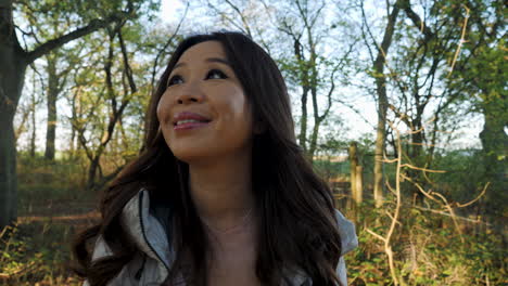 a close up shot of a smiling asian woman in a wood