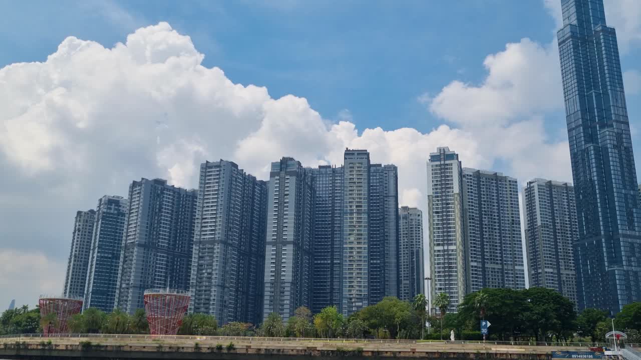 Panoramic view of Ho Chi Minh City’s skyline with Landmark 81 and surrounding high-rise buildings, filmed from a boat on the Saigon River under a cloudy sky