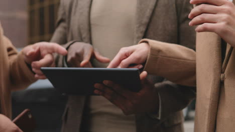 close-up view of african american man hands holding a tablet and caucasian male and female hands pointing something on its screen