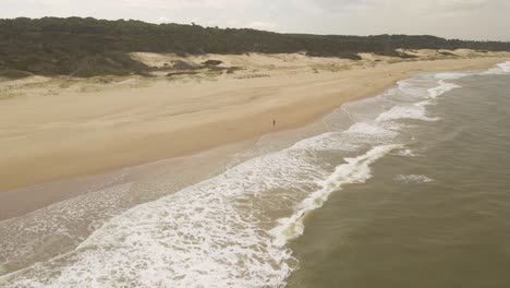 Man-running-on-Playa-Grande-beach-in-Punta-del-Diablo,-Uruguay