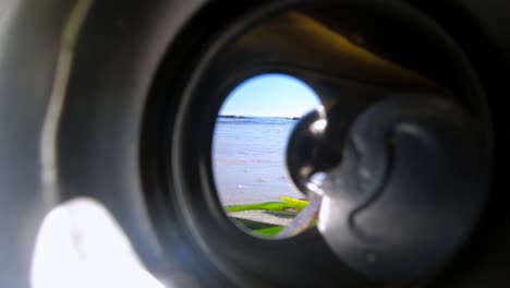 mirando a través de la apertura de una lata de bebida de aluminio descartada descuidadamente en la playa por una persona descuidada