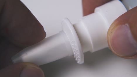 man taps on cap and opens nasal spray on light background