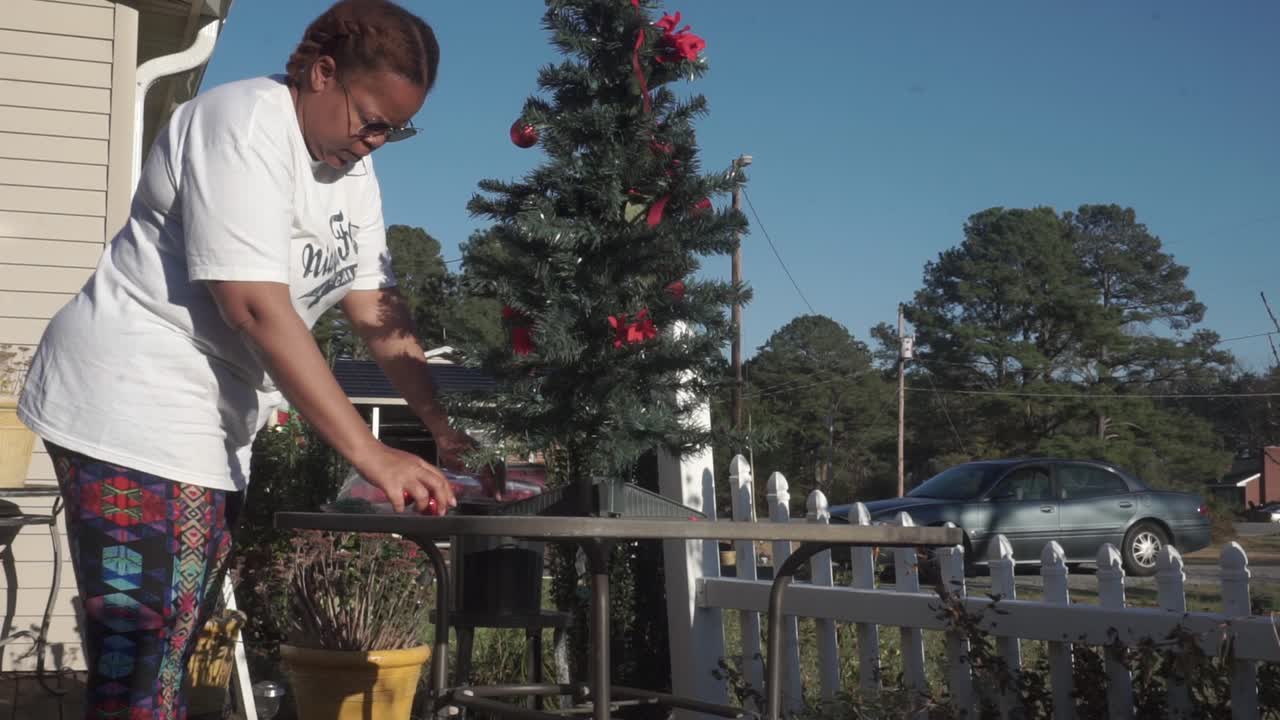 Black woman happily decorating Christmas tree