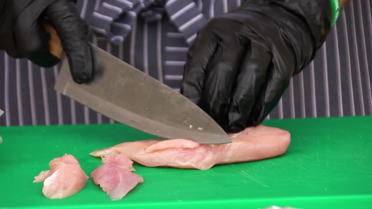 chef cortando pecho de pollo crudo