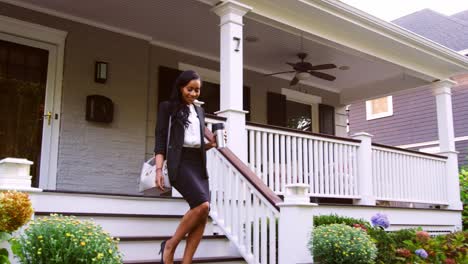 businesswoman with cup of coffee leaving suburban house for work