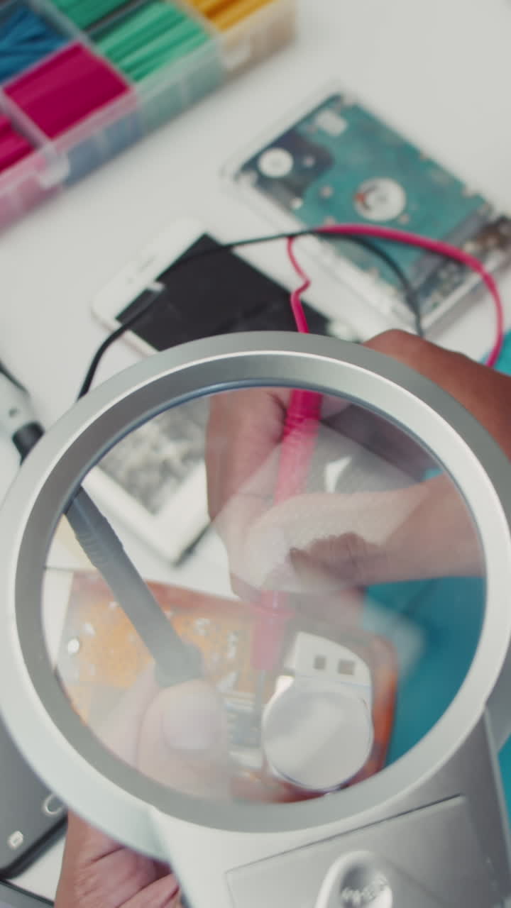 Technician Repairing Broken Phone Using Magnifying Glass