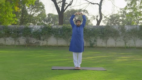 hombre indio haciendo postura básica de yoga en un parque