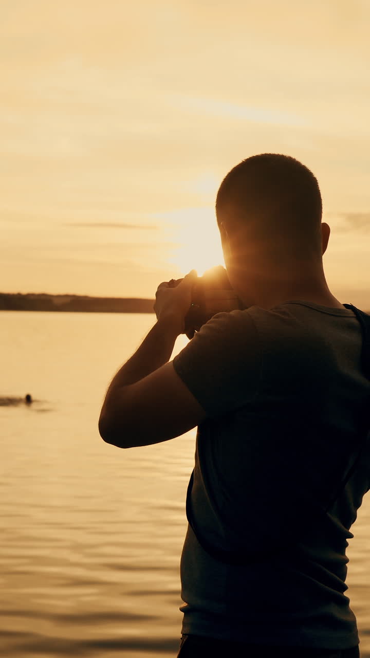 Photographer taking picture of sunset at local beach which is tourists point. Beautiful summer sunset. Vertical video
