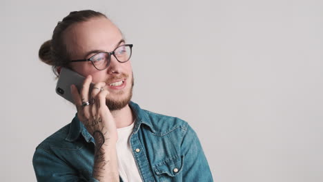 un joven caucásico hablando por teléfono.
