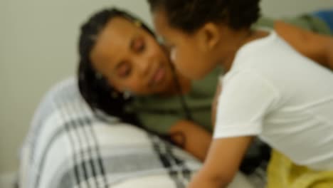 Front-view-of-young-black-mother-playing-with-her-son-on-bed-in-a-comfortable-home-4k