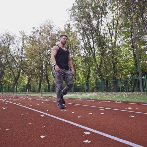 healthy athlete walking on the modern stadium. handsome sportsman lifting heavy weights on the nature background. slow motion.