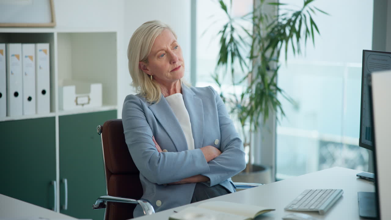 Mature Businesswoman Looking Thoughtful at Her Office Desk