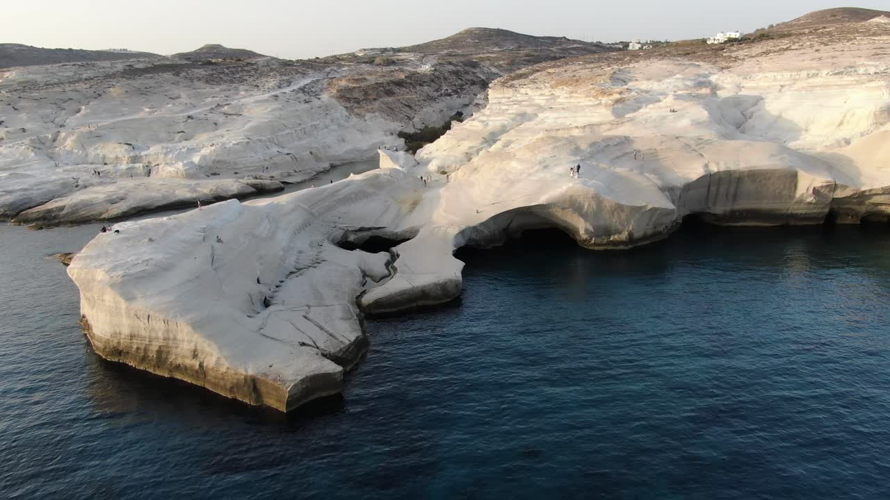 vista de avión no tripulado en grecia volando sobre una zona de roca blanca en forma de luna en la isla de milos al amanecer junto al mar azul oscuro