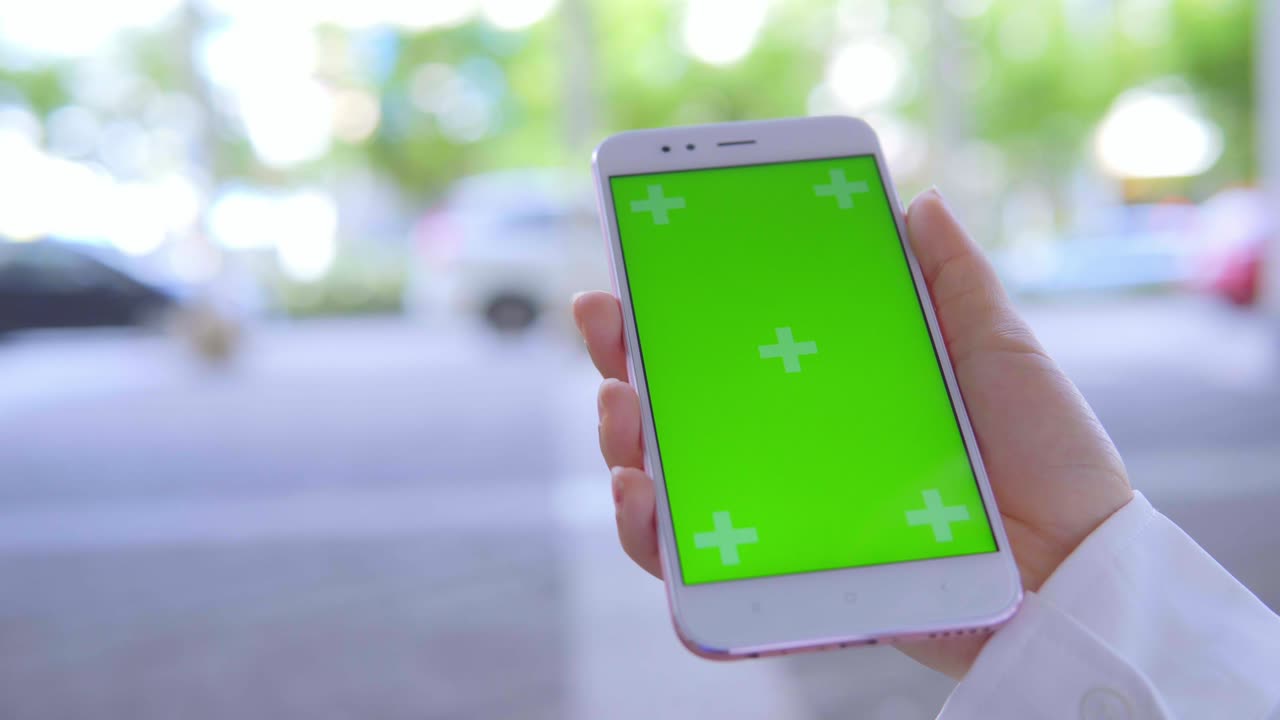 Business woman using smartphone with green screen on the street