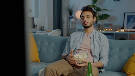 man watching tv with popcorn and beer