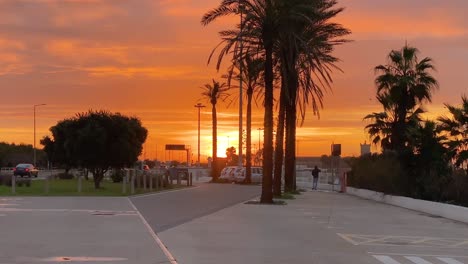 High-contrast-silhouettes-of-beach-parking-on-horizon-with-beautiful-deep-sunset-colours,-light-and-cloudy-sky,-Praia-de-Carcavelos,-Portugal