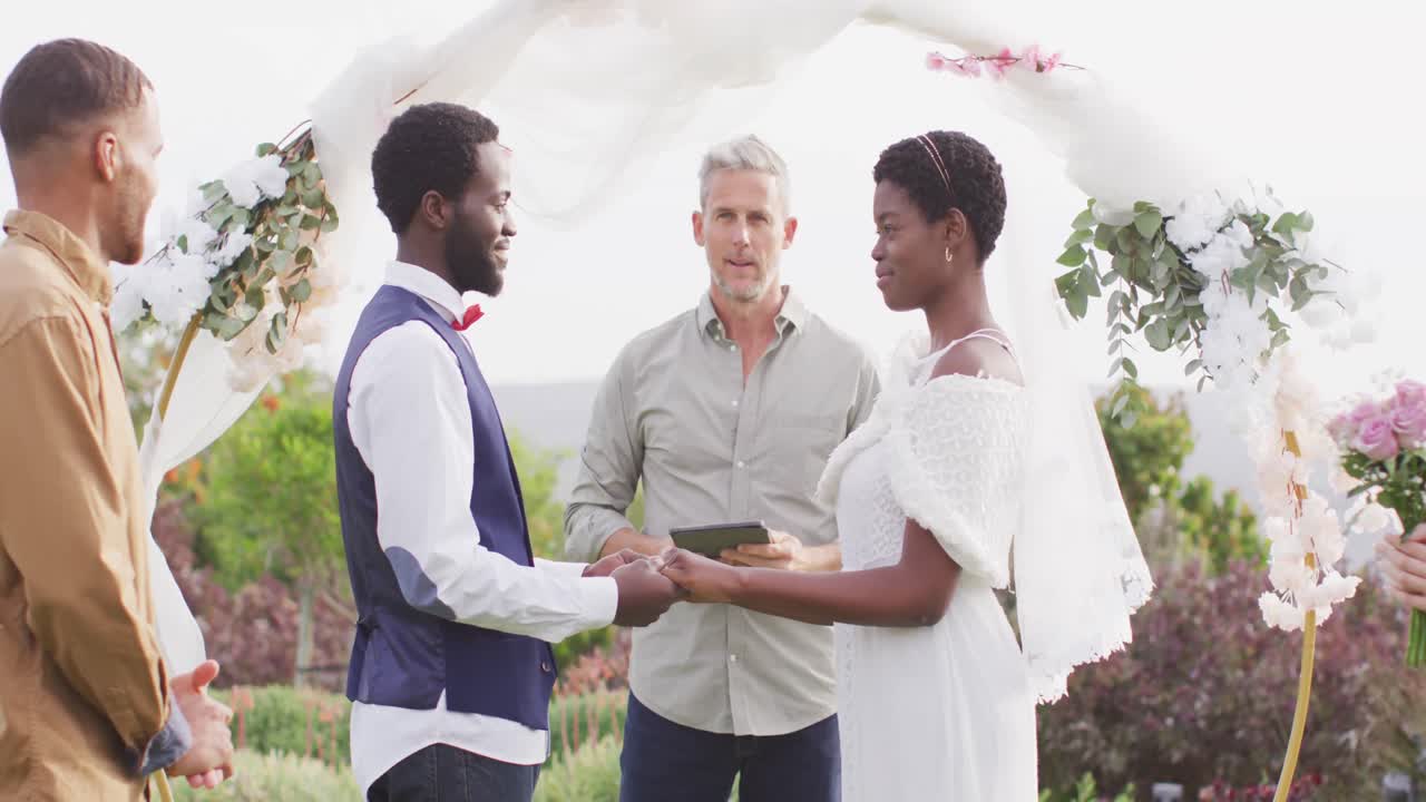 feliz pareja afroamericana cogida de las manos durante la boda