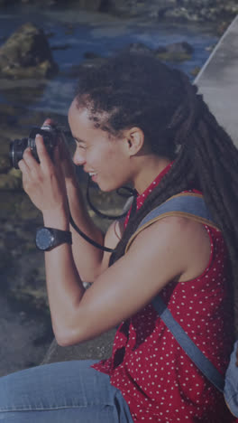 Animación-De-Puntos-De-Luz-Sobre-Una-Mujer-Birracial-Tomando-Fotos-Con-Una-Cámara-En-El-Paseo-Marítimo