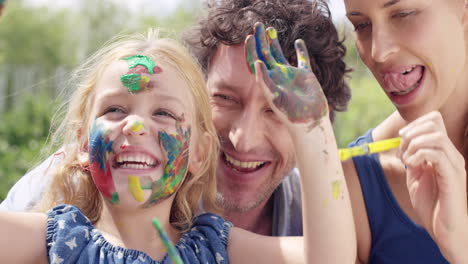 Glückliche-Familie-Mit-Kleinem-Mädchen,-Das-Kreativ-Mit-Mama-Und-Papa-Im-Garten-Malt