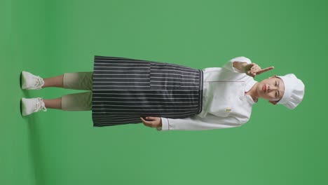 full body of asian woman chef pointing at you and disapproving with no index finger sign in the green screen background studio
