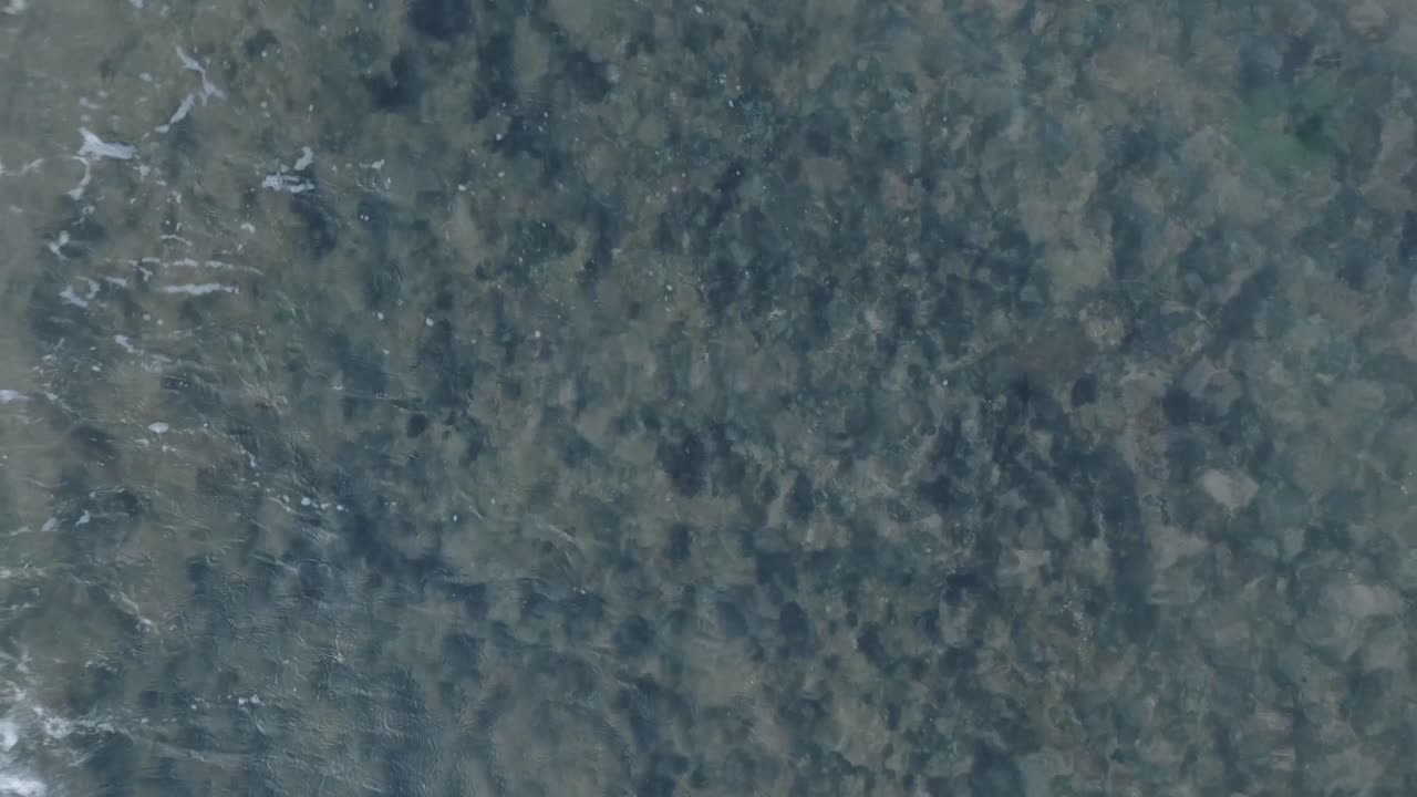 Top down descending drone shot over dead coral reef under shallow water in tropical Balangan Beach Uluwatu Bali Indonesia