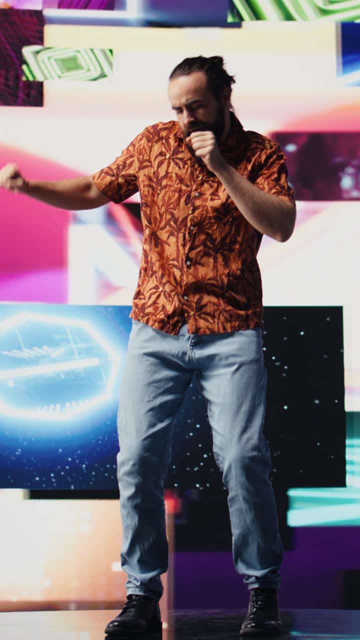 Vertical Video Young carefree guy performing with fun dance moves in glowing neon ambiance