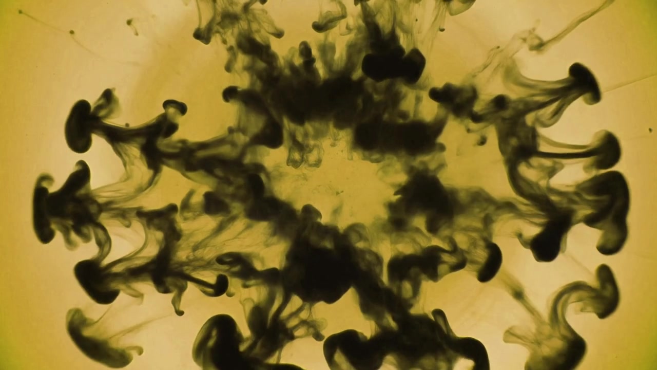 Inchiostro nero che cade e si espande in un liquido giallo