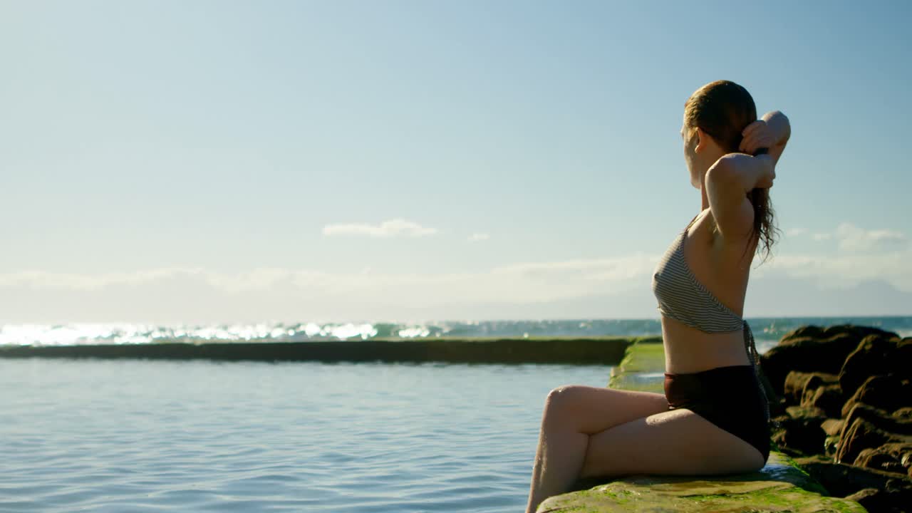 Mulher relaxando na piscina na praia 4k