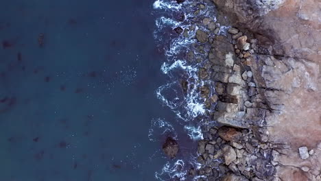 waves breaking against the rocky shore near rancho palos verdes in southern california - straight down aerial view