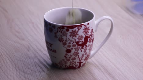 tea bag dipping into a cup of hot water