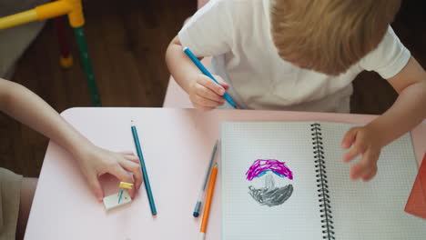 Elder-girl-plays-with-eraser-and-pins-and-toddler-boy-draws