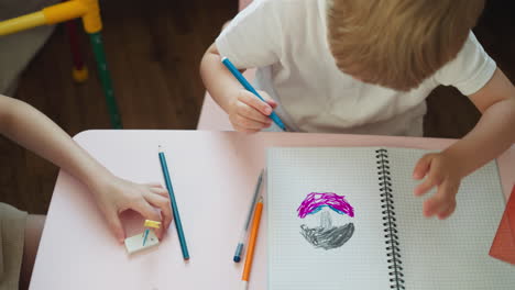 Elder girl plays with eraser and pins and toddler boy draws