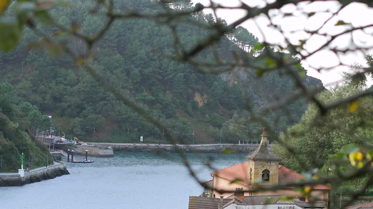 Static shot shifts focus from a branch to reveal a scenic view of Pasaia Bay. Gipuzkoa, Spain