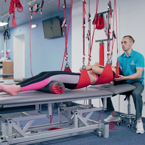 woman is hanging on special suspension ropes in rehabilitation center. modern equipment for undergoing physiotherapy for a young female.personal trainer and a patient in modern center.
