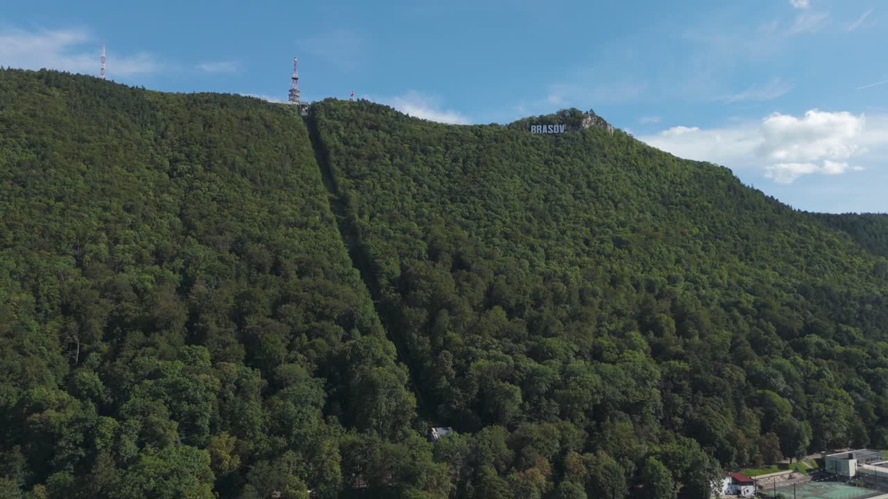 Letecký pohled na lanovku Tâmpa a ikonický nápis Brașov na svahu nad městem v Rumunsku