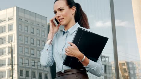 feliz mujer de negocios sonriente hablando por teléfono móvil y sosteniendo documentos