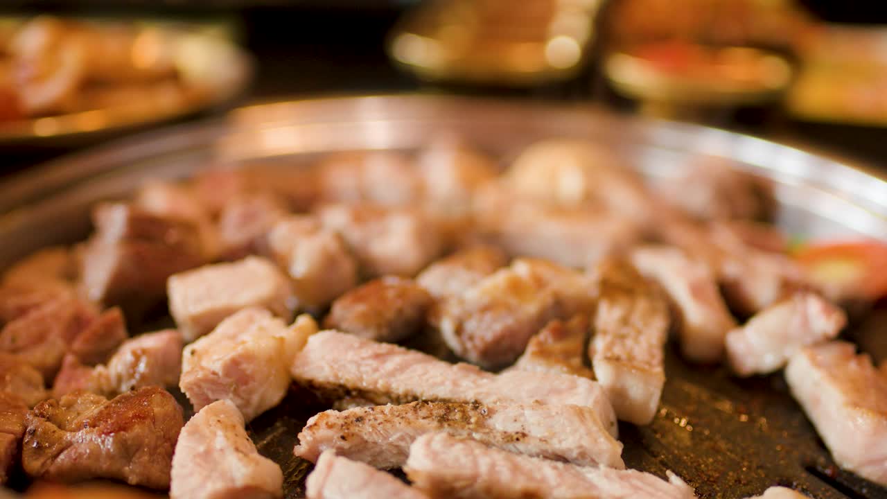 Close-up of pork belly grilling on hotplate, steam rising, warm lighting, shallow depth of field