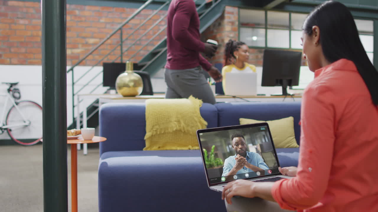 mujer de negocios biracial que usa una computadora portátil para una videollamada con un colega de negocios afroamericano