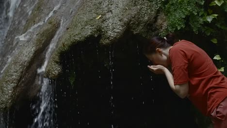 woman drinking water from waterfall