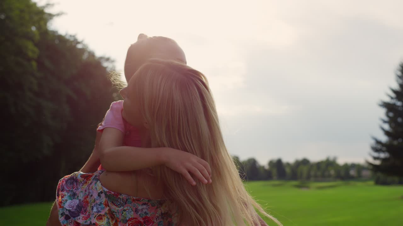 mujer alegre dando vueltas a la niña en sus brazos en el jardín. madre recogiendo a su hija.