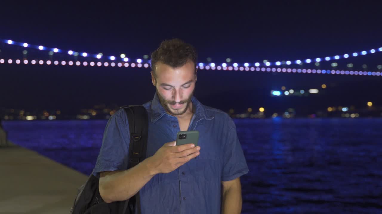 Giovane uomo felice che usa il telefono mentre cammina.